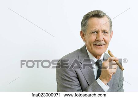 Senior businessman smiling at camera, holding cigar, portrait View Large Photo Image Stock Image - Senior businessman smiling at camera, holding cigar, portrait. Fotosearch