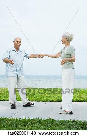 Senior couple dancing on sidewalk overlooking ocean, full length View Large Photo Image Stock Photo - Senior couple dancing on sidewalk overlooking ocean, full length. Fotosearch