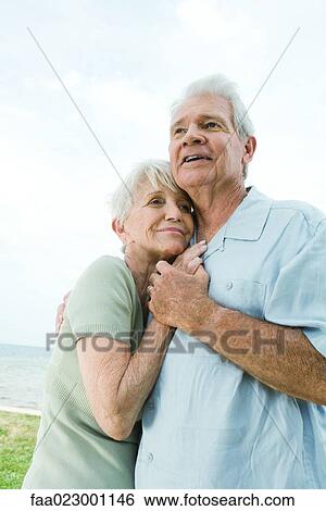 Senior couple hugging, looking away, waist up View Large Photo Image Stock Photograph - Senior couple hugging, looking away, waist up. Fotosearch