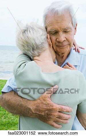 Stock Image - Senior couple hugging, man closing eyes, close-up. Fotosearch