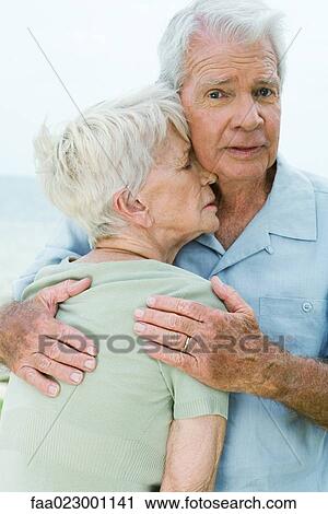Senior couple, man holding woman tightly against him, looking at camera View Large Photo Image Stock Image - Senior couple, man holding woman tightly against him, looking at camera. Fotosearch