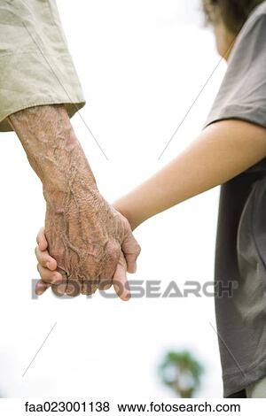 Stock Photo - Senior woman and boy holding hands, cropped view, close-up. Fotosearch