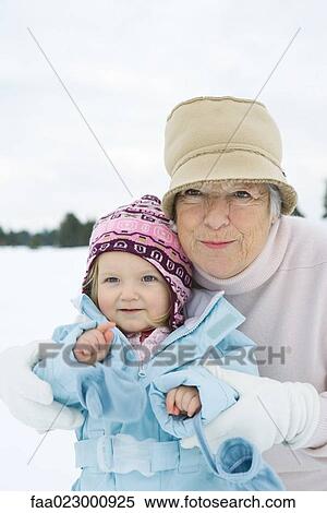 Senior woman embracing toddler girl, both smiling, dressed in winter clothing, portrait View Large Photo Image Stock Photography - Senior woman embracing toddler girl, both smiling, dressed in winter clothing, portrait. Fotosearch