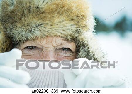 Stock Photo - Senior woman pulling up turtleneck over face, close-up, portrait. Fotosearch