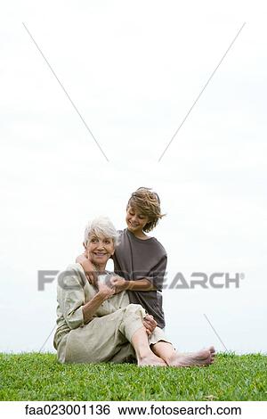 Senior woman sitting on grass, grandson handing her gift, full length View Large Photo Image Stock Photograph - Senior woman sitting on grass, grandson handing her gift, full length. Fotosearch