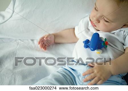 Sleeping baby with toy on stomach, high angle view View Large Photo Image Picture - Sleeping baby with toy on stomach, high angle view. Fotosearch