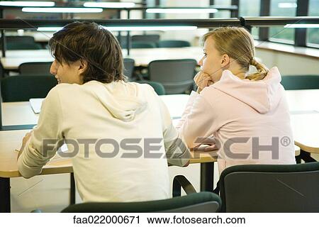 Stock Image - Students sitting in library, rear view. Fotosearch