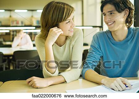 Students studying in university library, smiling at each other View Large Photo Image Stock Photograph - Students studying in university library, smiling at each other. Fotosearch