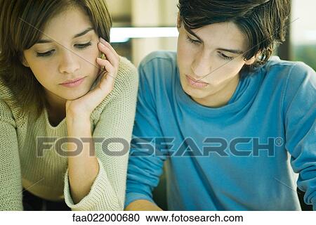 Stock Image - Students studying together, looking down, portrait. Fotosearch