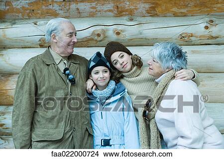 Picture - Teen and preteen girls with grandparents, standing in front of log cabin with arms around each other, portrait. Fotosearch