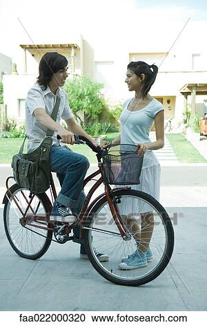 Teen boy on bike speaking to young female friend in residential neighborhood, full length View Large Photo Image Stock Image - Teen boy on bike speaking to young female friend in residential neighborhood, full length. Fotosearch