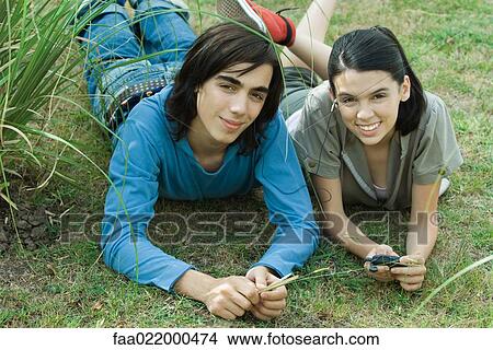 Teen couple listening to MP3 player together, lying on grass View Large Photo Image Picture - Teen couple listening to MP3 player together, lying on grass. Fotosearch