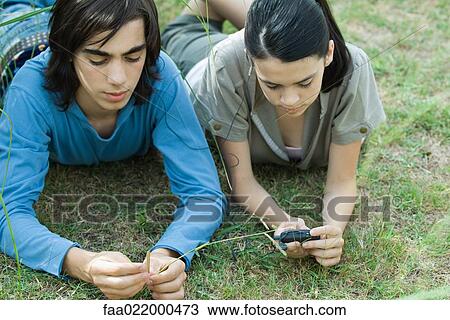 Stock Image - Teen couple listening to MP3 player together, lying on grass. Fotosearch