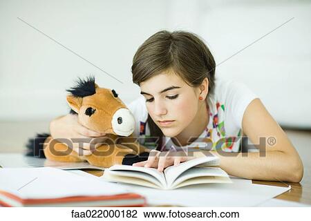 Teen girl lying on floor, holding stuffed toy horse and doing homework View Large Photo Image Stock Image - Teen girl lying on floor, holding stuffed toy horse and doing homework. Fotosearch