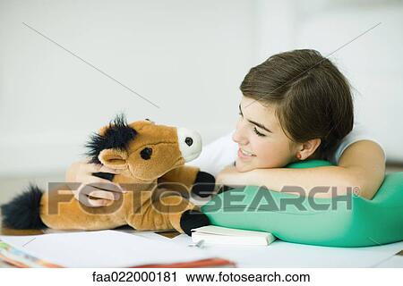 Teen girl lying on floor, smiling at stuffed toy horse View Large Photo Image Stock Image - Teen girl lying on floor, smiling at stuffed toy horse. Fotosearch