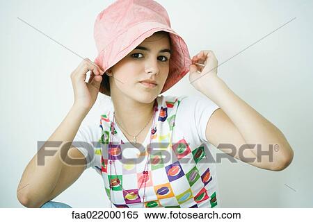 Teen girl putting on hat, portrait View Large Photo Image Stock Photography - Teen girl putting on hat, portrait. Fotosearch