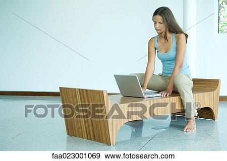Teen girl sitting on bench, using laptop computer, looking down View Large Photo Image Stock Photo - Teen girl sitting on bench, using laptop computer, looking down. Fotosearch