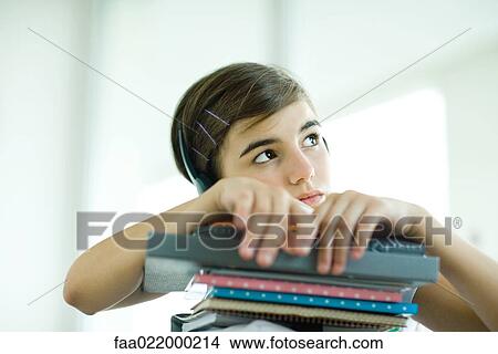 Teen girl with stack of homework, listening to headphones, portrait View Large Photo Image Picture - Teen girl with stack of homework, listening to headphones, portrait. Fotosearch