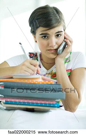 Teen girl with stack of homework, using cell phone and writing in notebook View Large Photo Image Stock Photography - Teen girl with stack of homework, using cell phone and writing in notebook. Fotosearch