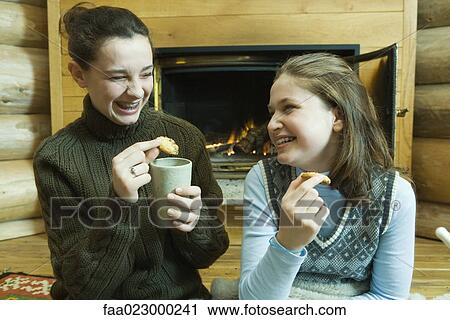 Teen girls having snack by fire place, laughing View Large Photo Image Stock Image - Teen girls having snack by fire place, laughing. Fotosearch