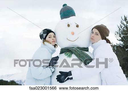 Stock Photograph - Teen girls leaning against snowman. Fotosearch