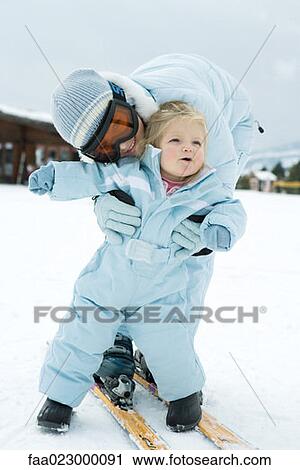 Teenage girl bending over, embracing toddler, both dressed in ski-suits View Large Photo Image Stock Image - Teenage girl bending over, embracing toddler, both dressed in ski-suits. Fotosearch