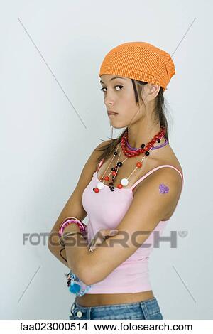 Teenage girl biting lip, arms folded, sideways glance at camera View Large Photo Image Picture - Teenage girl biting lip, arms folded, sideways glance at camera. Fotosearch