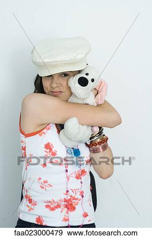 Stock Photo - Teenage girl embracing stuffed toy, smiling at camera, portrait. Fotosearch