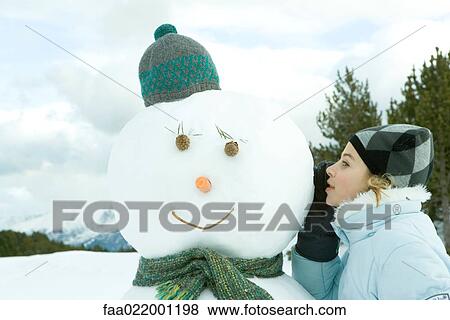 Teenage girl leaning against snowman, whispering, side view View Large Photo Image Stock Photo - Teenage girl leaning against snowman, whispering, side view. Fotosearch