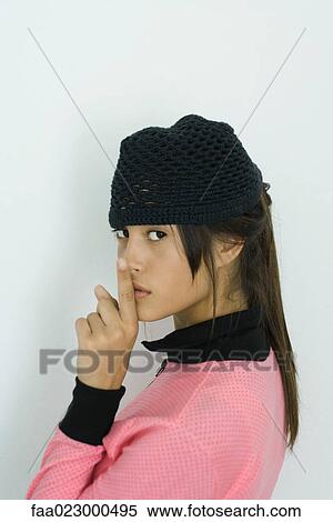 Teenage girl looking over shoulder at camera, finger on lips View Large Photo Image Stock Photography - Teenage girl looking over shoulder at camera, finger on lips. Fotosearch