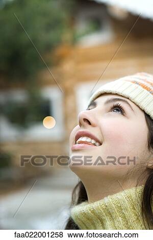 Stock Photo - Teenage girl looking up, close-up, chalet in background. Fotosearch