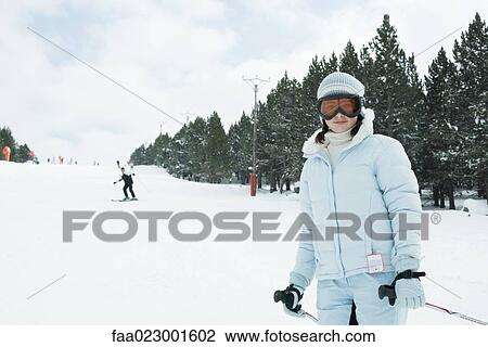 Stock Image - Teenage girl on skis, smiling at camera. Fotosearch