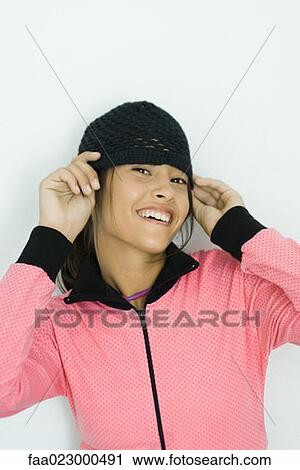 Teenage girl putting on knit hat, smiling at camera, portrait View Large Photo Image Stock Image - Teenage girl putting on knit hat, smiling at camera, portrait. Fotosearch