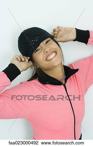 Teenage girl putting on knit hat, smiling at camera, portrait View Large Photo Image Stock Image - Teenage girl putting on knit hat, smiling at camera, portrait. Fotosearch