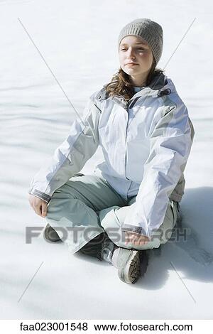 Stock Photo - Teenage girl sitting indian style on snow with eyes closed and head back, full length. Fotosearch