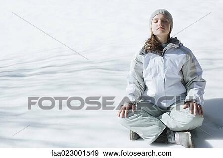 Stock Photo - Teenage girl sitting indian style on snow with eyes closed and head back, full length. Fotosearch