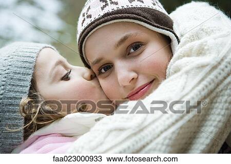Teenage girl smiling at camera, sister kissing her on cheek, portrait View Large Photo Image Stock Image - Teenage girl smiling at camera, sister kissing her on cheek, portrait. Fotosearch