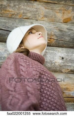 Stock Photography - Teenage girl wearing hat and turtleneck, looking up, low angle view, portrait. Fotosearch