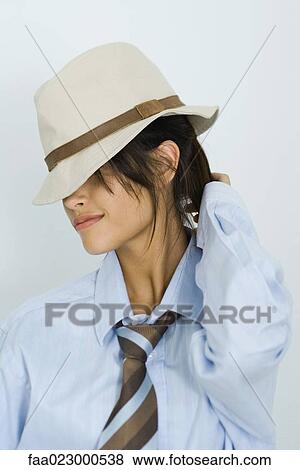 Stock Photo - Teenage girl wearing hat and tie, eyes covered, portrait. Fotosearch