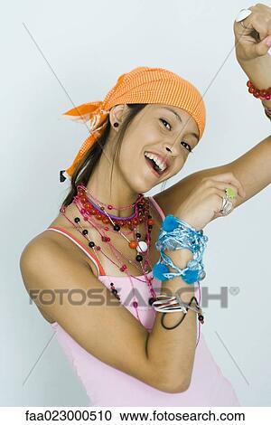 Teenage girl wearing lots of jewelry, smiling at camera, arms raised View Large Photo Image Stock Image - Teenage girl wearing lots of jewelry, smiling at camera, arms raised. Fotosearch