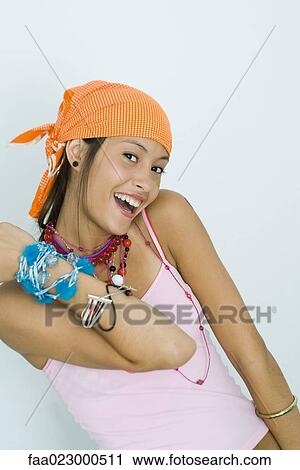 Stock Image - Teenage girl wearing lots of jewelry, smiling at camera, portrait. Fotosearch