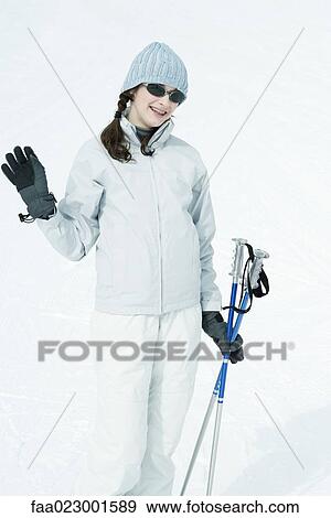 Stock Photo - Teenage girl with ski gear, waving at camera, portrait. Fotosearch