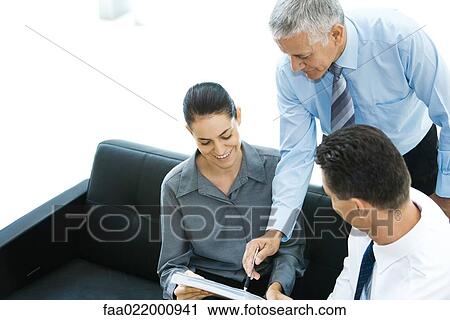 Three business associates looking at file together, one pointing View Large Photo Image Stock Image - Three business associates looking at file together, one pointing. Fotosearch