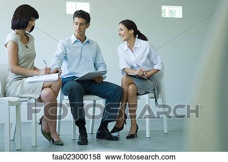 Three business associates sitting on chairs, holding documents on laps, talking View Large Photo Image Stock Photo - Three business associates sitting on chairs, holding documents on laps, talking. Fotosearch