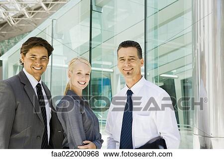 Stock Photo - Three business associates smiling at camera, waist up, group portrait. Fotosearch