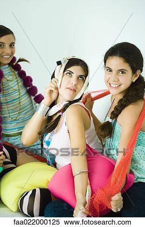 Three young female friends dressing up with scarves, one making face View Large Photo Image Stock Photography - Three young female friends dressing up with scarves, one making face. Fotosearch