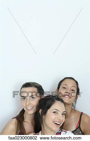 Stock Image - Three young female friends smiling, head and shoulders, portrait. Fotosearch