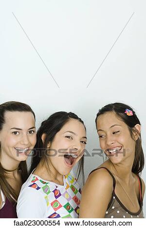 Three young friends smiling together, one looking at camera, portrait View Large Photo Image Picture - Three young friends smiling together, one looking at camera, portrait. Fotosearch