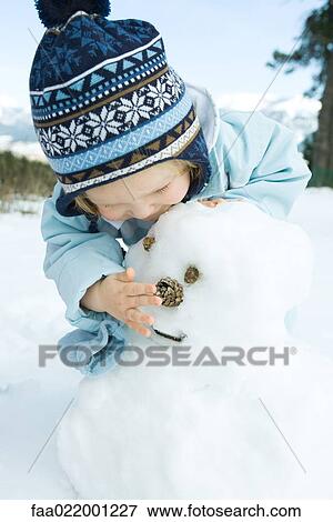 Toddler girl building snowman, bending over View Large Photo Image Stock Photo - Toddler girl building snowman, bending over. Fotosearch