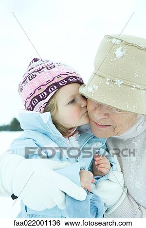 Toddler girl kissing grandmother on cheek in snow, close-up View Large Photo Image Stock Photograph - Toddler girl kissing grandmother on cheek in snow, close-up. Fotosearch
